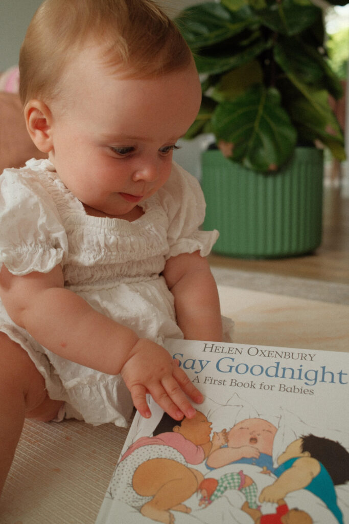 Baby Charlotte reading a book called Say Goodnight